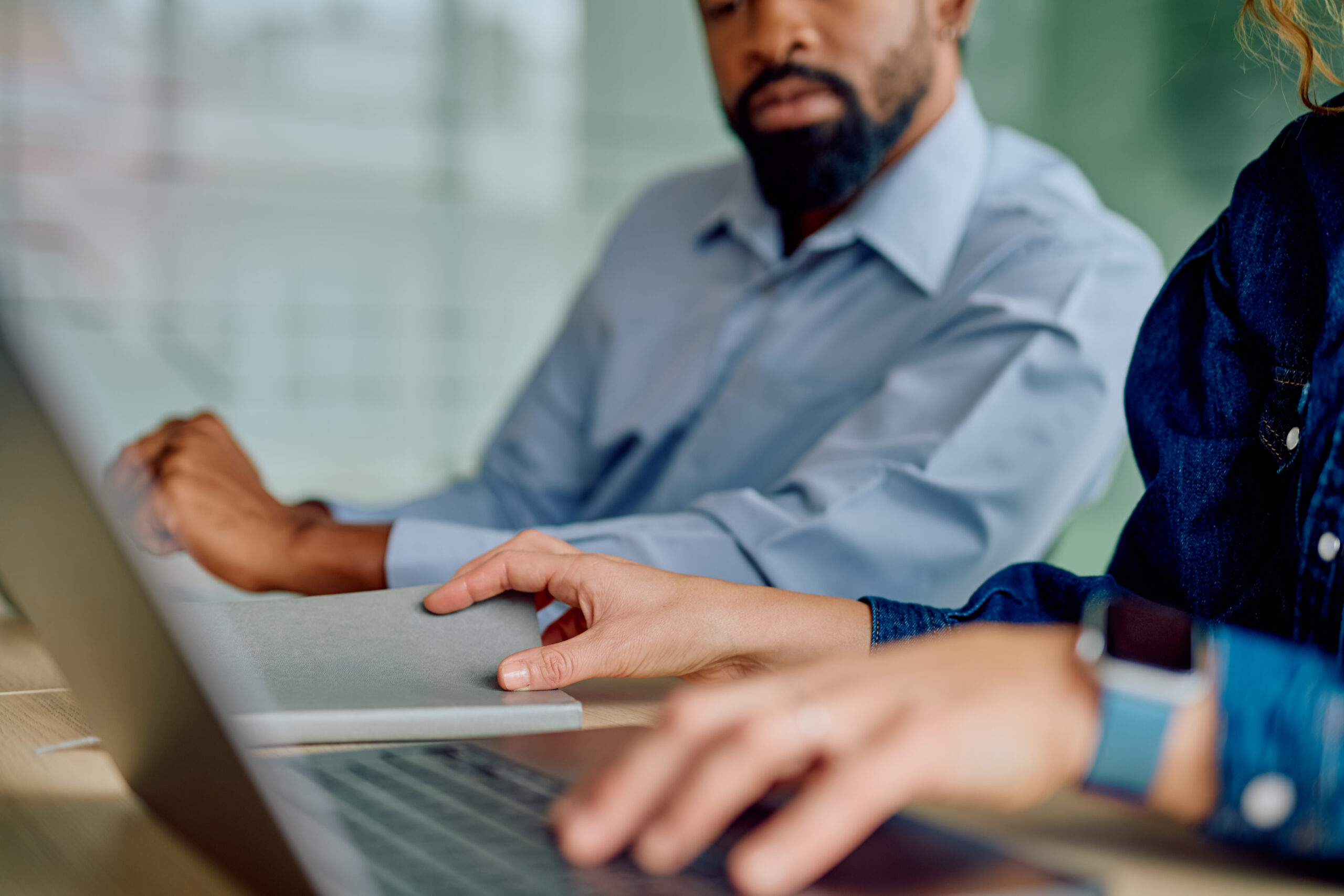 Business colleagues collaborating on laptop in office meeting